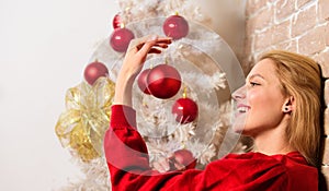 Waiting for christmas. Girl wear red dress sit near christmas tree. Woman happy hold christmas ball ornament. Winter