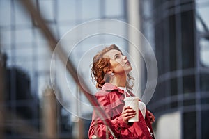 Waiting for the good weather. Adult pretty woman in warm red coat have walk in the city at her weekends time