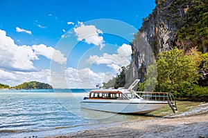 Waiting for passenger. Snow white premium speedboat on the shore of a tropical island. Moored on a sandy beach, Tropics and rocks