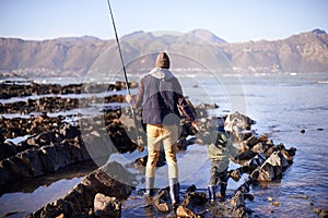 Waiting for the perfect catch. a father and son fishing by the sea.