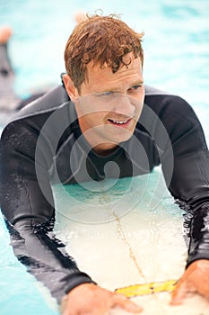 Waiting for the perfect wave. Shot of a handsome young man enjoying a surf in clear blue water.