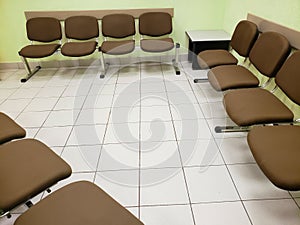 waiting room with light green walls, white floor and comfortable chairs in brown