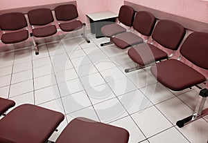 waiting room with light pink walls, white floor and comfortable chairs in brown