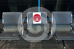 waiting room with metal chairs with a red sign for observing the distance