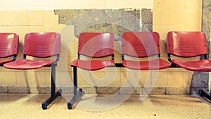 Waiting room, red chairs placed against a deteriorated wall