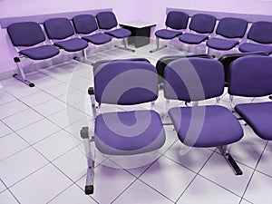 waiting room with violet walls, white floor and comfortable chairs in purple