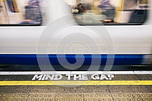 Subway train at the station from the platform seeing the Mind the Gap letters