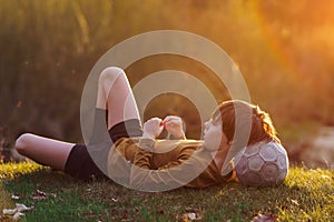 Waiting for workout in summer morning at sports camp. Teenager lies on mown grass , resting his head on soccer ball.