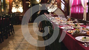 Waitress arranges plates of food on table in restaurant for corporate dinner, banqueting hall