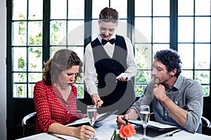 Waitress assisting a couple while selecting menu