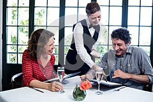 Waitress assisting a couple while selecting menu