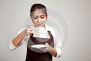 Waitress or barista in apron drinking coffee