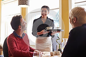 Waitress bringing coffees to a male couple at a restaurant