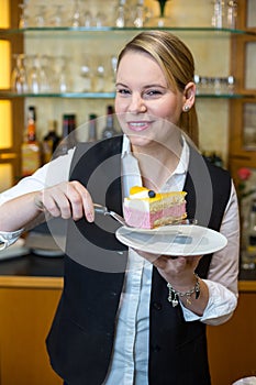 Waitress at cafï¿½ presenting cake on plate