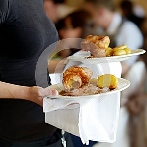 Waitress carrying two plates with meat dish