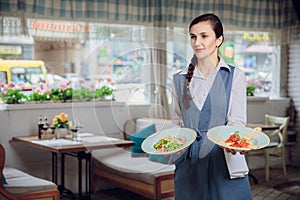 Waitress is carrying two plates with restautant delicious dishes