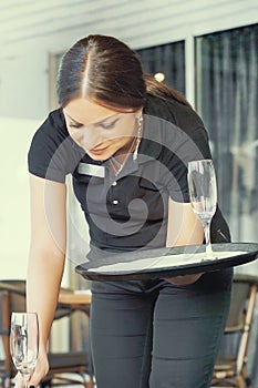 The waitress is carrying a wine glasses