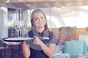 The waitress is carrying a wine glasses