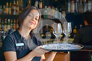 Waitress is carrying a wine glasses