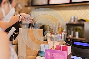 Waitress at counter giving eco friendly paper bag with take away drink in cafe.