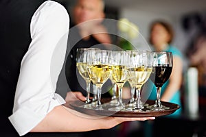 Waitress with dish of champagne and wine glasses