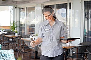 The waitress is carrying a wine glasses