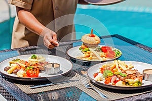 Waitress hand serving lunch in restaurant at hotel, holidays, vacations concept