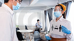 The waitress held a sign that explained the social distancing to customers for prevent the spread of pandemic Covid-19 or