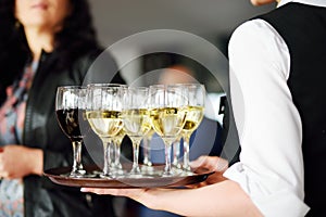 Waitress holding a dish of champagne and wine glasses at festive event