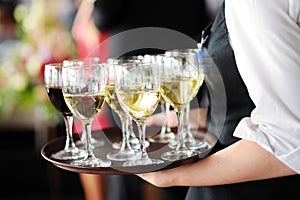 Waitress holding a dish of champagne and wine glasses at festive event