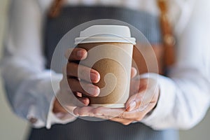 A waitress holding and serving a paper cup of hot coffee