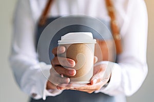 A waitress holding and serving a paper cup of hot coffee photo