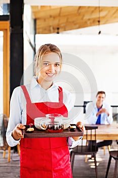 Waitress holding a tray with tea and coffee