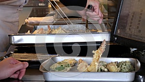 a waitress makes up an order of tempura prawns and vegetables at a restaurant
