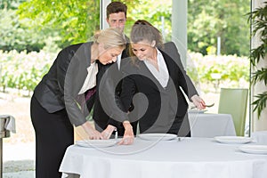 Waitress with manager setting table in restaurant