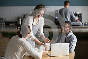 Waitress and multiracial visitors laughing at funny joke in cafe