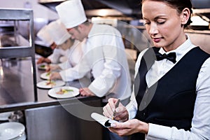 Waitress with note pad in commercial kitchen