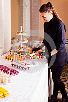 Waitress occupation. Woman servicing dessert table in restaurant during catering the event