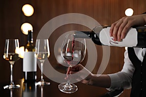 Waitress pouring wine into glass in restaurant
