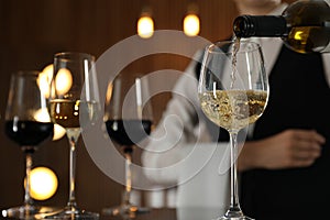 Waitress pouring wine into glass in restaurant