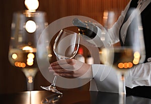 Waitress pouring wine into glass in restaurant