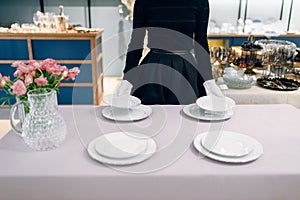 Waitress puts dishes for banquet, table setting