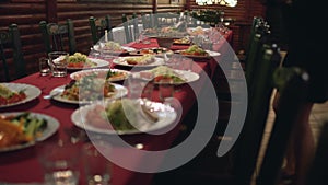 Waitress puts plates of food on the table in restaurant or cafe, catering in banqueting hall for corporate dinner