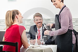 Waitress serve wine to couple