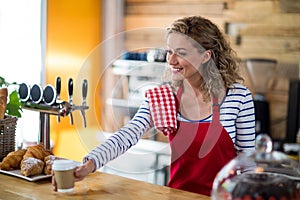 Waitress serving a cup of coffee to customer in cafÃÂ©