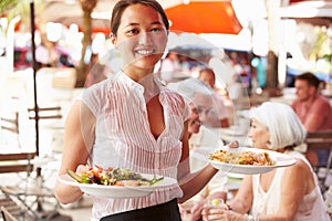 Waitress Serving Food At Outdoor Restaurant