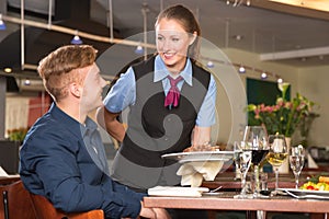 Waitress serving the meal to guest in restaurant photo