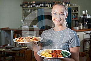 Waitress Serving Plates Of Food In Restaurant