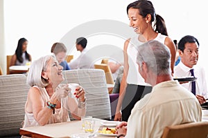 Waitress Serving Senior Couple Breakfast In Hotel Restaurant