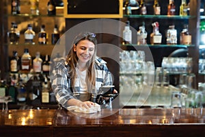 Waitress standing in bar and wiping and polishing beer glass. Bartender woman working in bar counter, preparing and cleaning, work